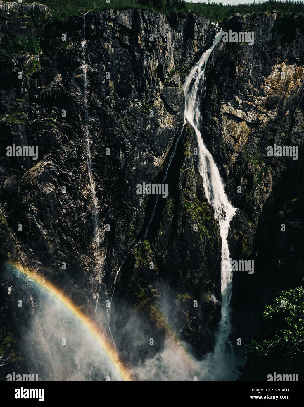 Vertical shot of a waterfall rapidly flowing down from the high cliff ...