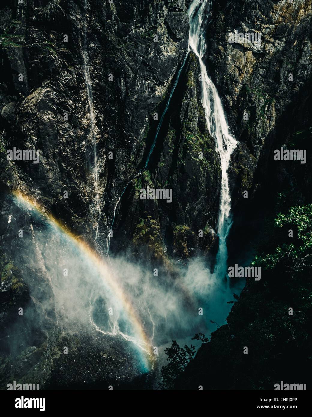 Vertical shot of a waterfall rapidly flowing down from the high cliff ...