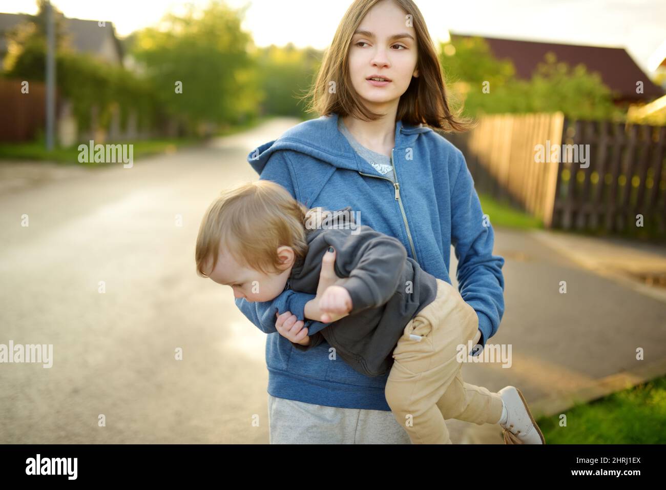 Cute big sister cuddling with her toddler brother. Adorable teenage