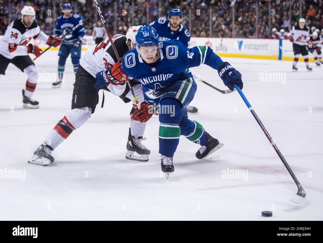 Vancouver Canucks' Troy Stecher, front, reaches for the puck while being  checked by New Jersey Devils' Kurtis Gabriel during the first period of an  NHL hockey game in Vancouver, on Friday March
