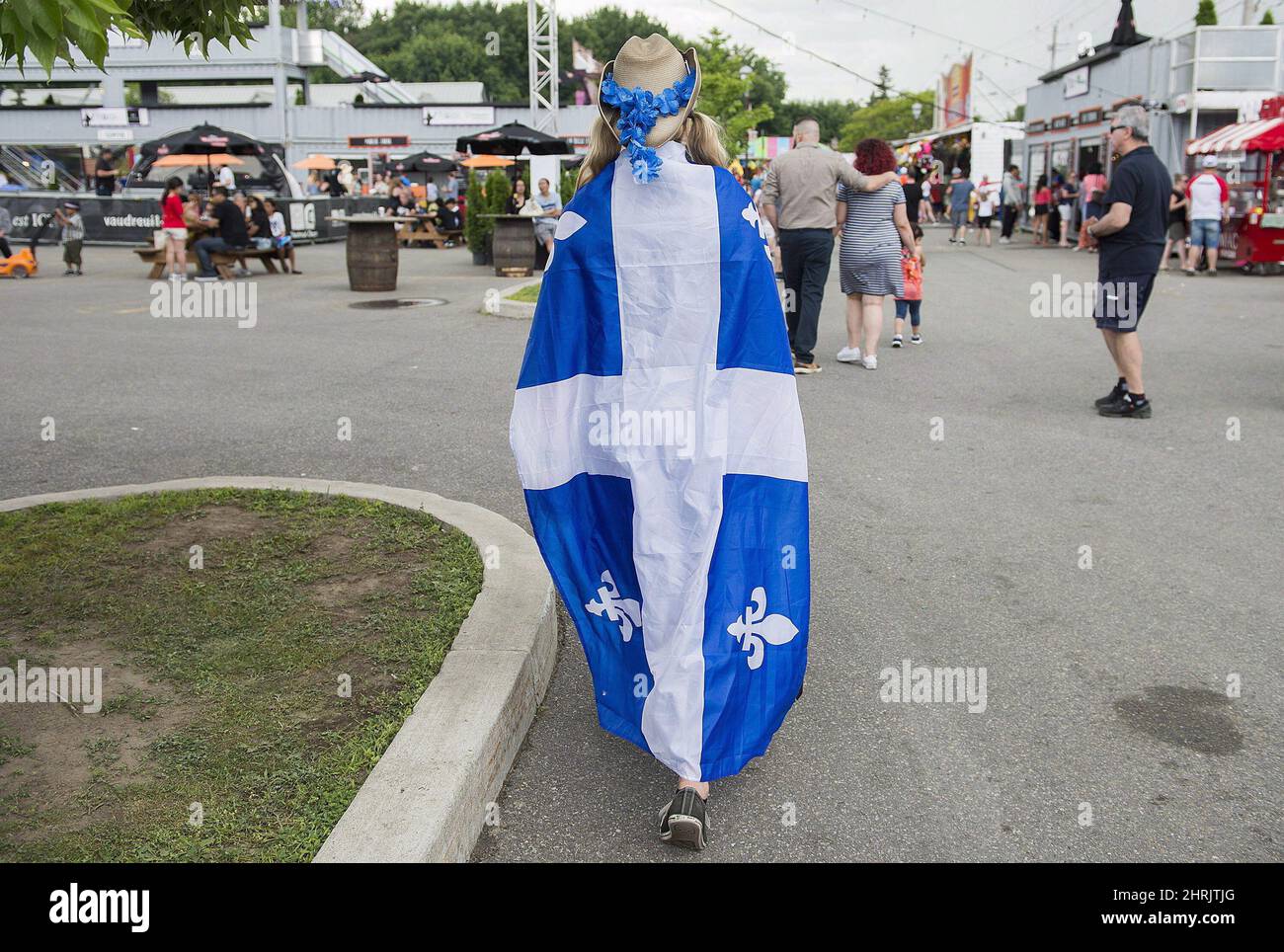 A woman is draped in a Quebec flag as she attends a Saint-Jean Baptiste day  celebration in a town west of Montreal, Sunday, June 24, 2018. One Montreal  neighbourhood's decision to rebrand