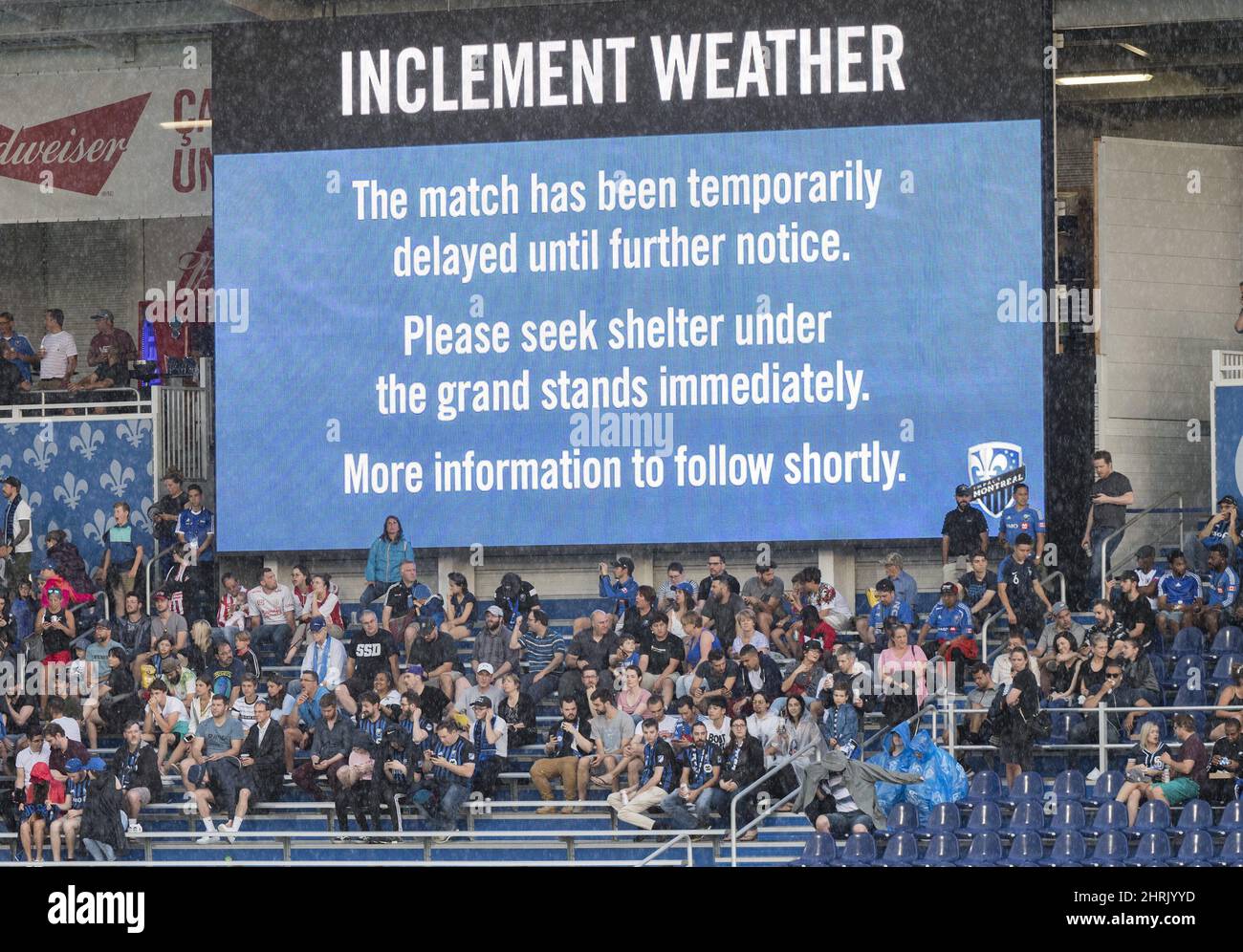 Fans seek shelter during a weather delay to the start of an MLS soccer