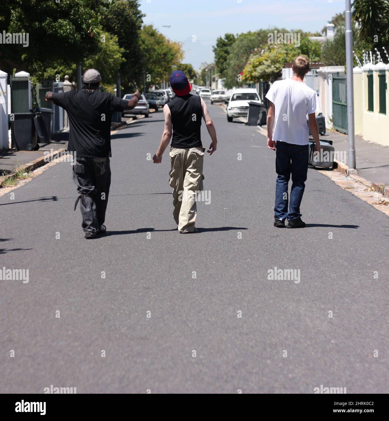 We run these streets. Shot of three young men walking down a suburban street. Stock Photo
