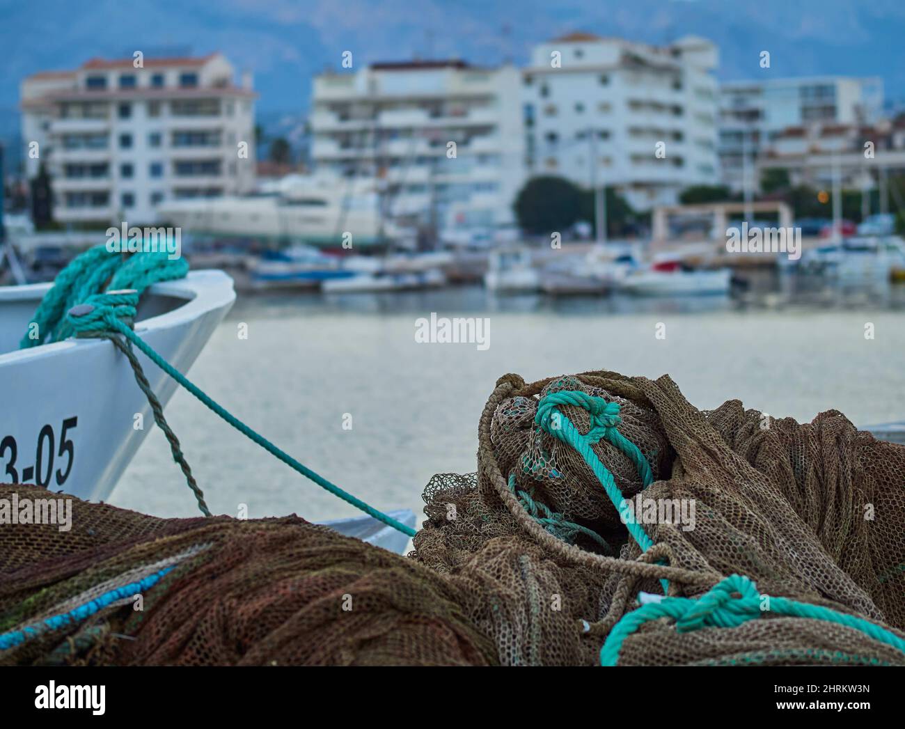Closeup of fishing nets and ropes in boats on the water with a town in