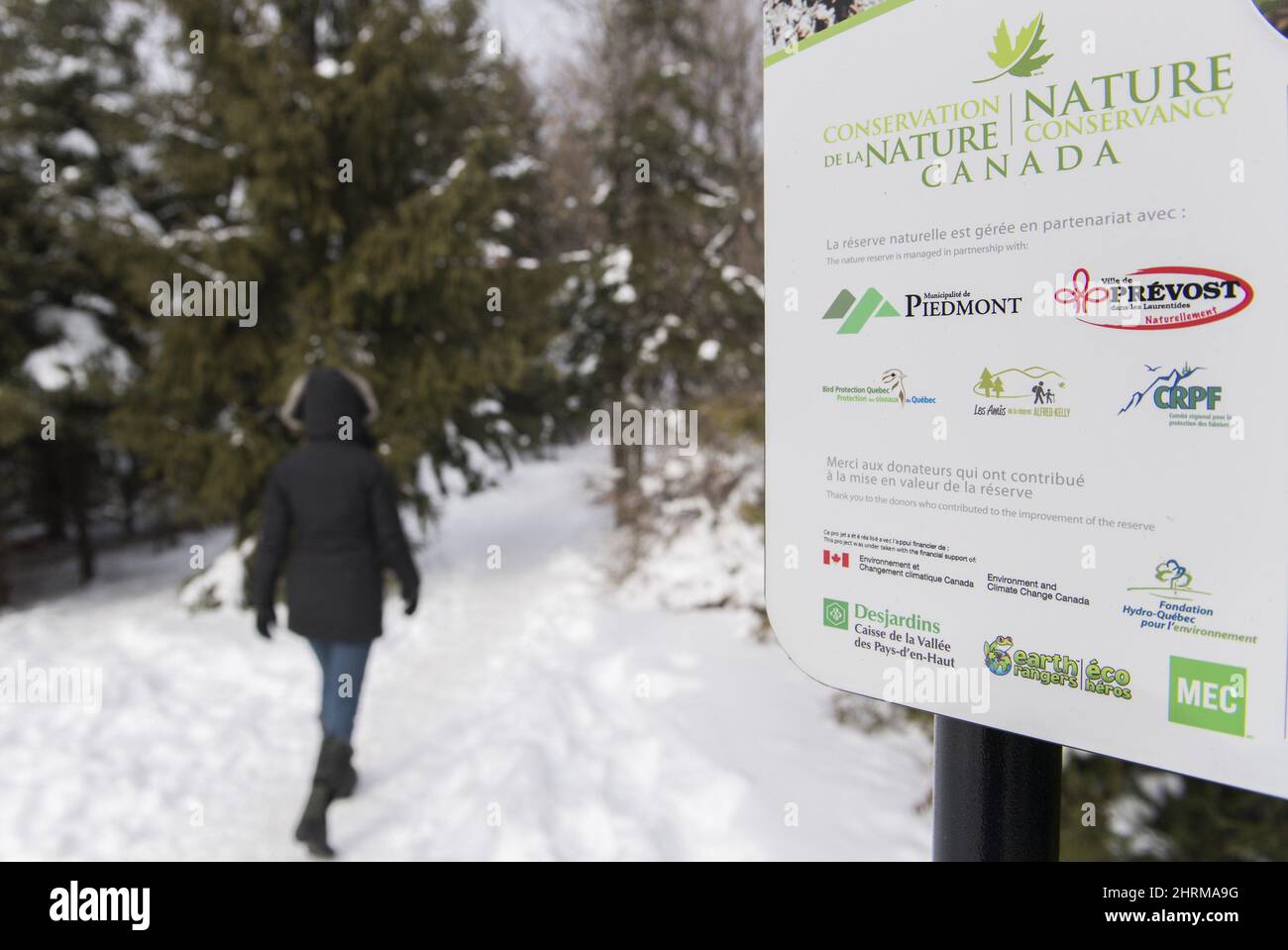 A woman walks by a sign for the Nature Conservancy of Canada at the ...