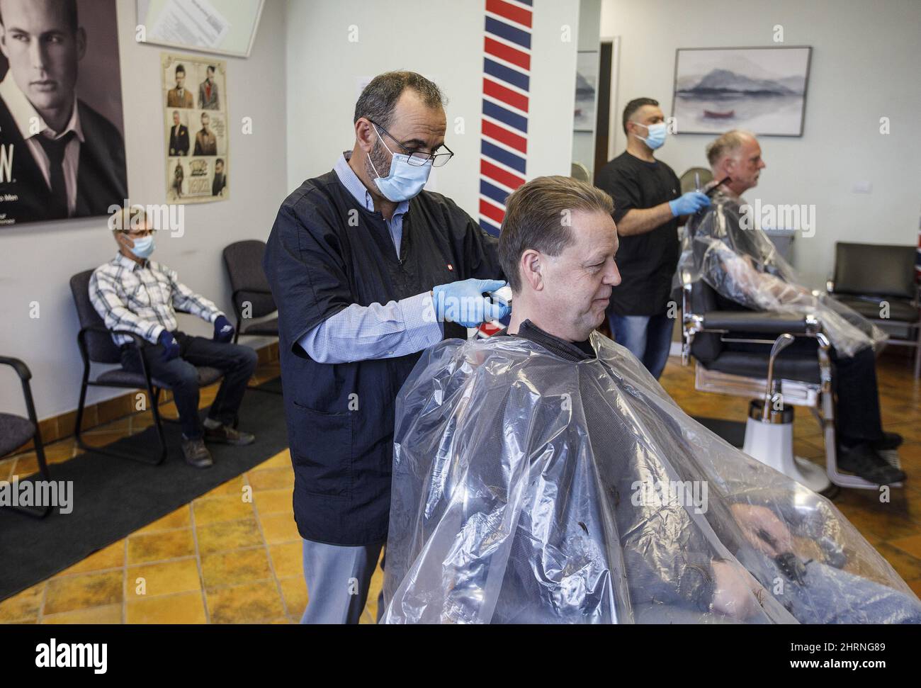 Customers get their hair cut by barbers Ted Alkadri, left and Billy Salla at Universal Barber Shop as businesses reopen during the COVID-19 pandemic, in Edmonton on Thursday May 14, 2020. THE CANADIAN PRESS/Jason Franson Stock Photo