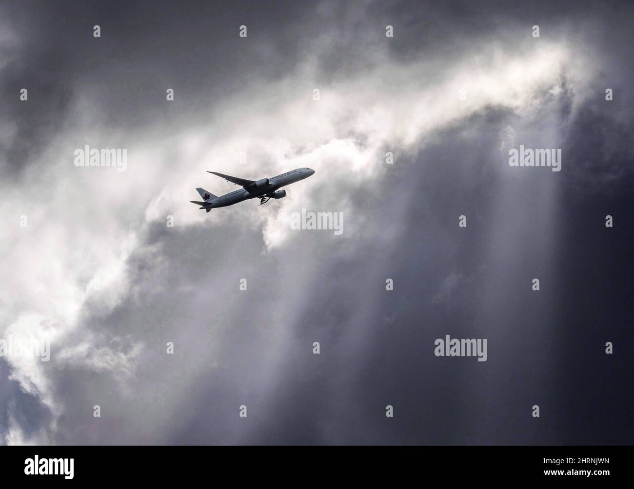 An Air Canada plane flies underneath dark clouds illuminated by some sun rays above Frankfurt, Germany, Thursday, March 2, 2017. Aimia Inc. says it plans to defend itself against a move by Air Canada in Quebec Superior Court to halt a merger that the smaller company sees as key to its corporate reinvention. THE CANADIAN PRESS/AP-Frank Rumpenhorst/dpa via AP Stock Photo