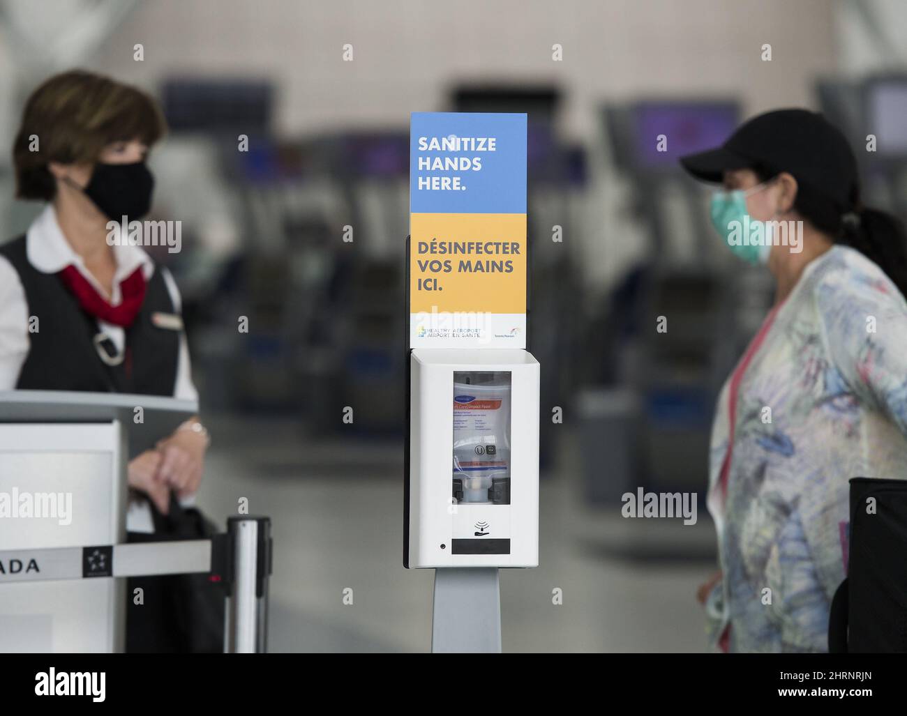 A lady talks with an Air Canada employee next to a hand sanitizer station at Toronto's Pearson