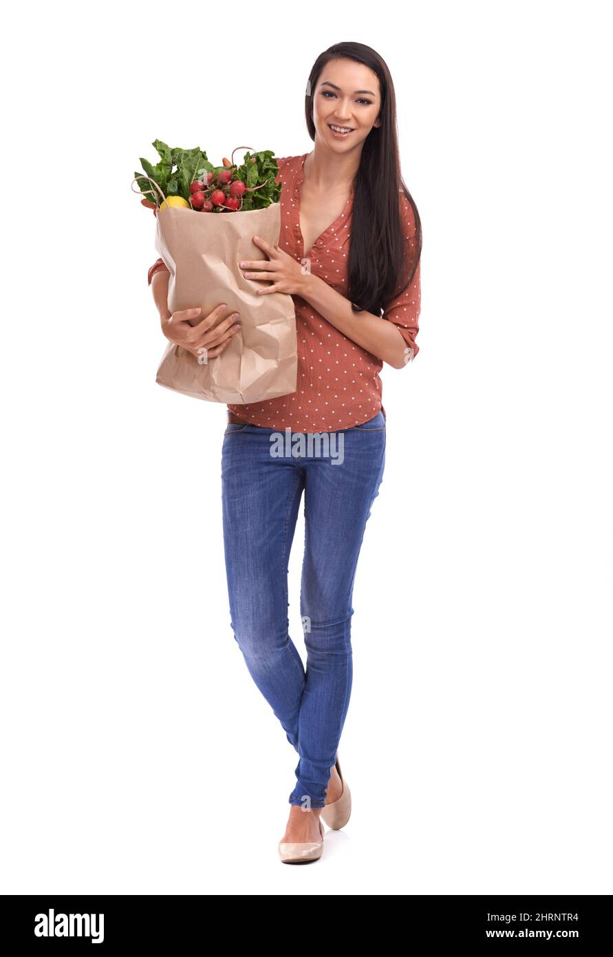 Thats my grocery shopping done. Studio shot of a young woman carrying a bag of groceries isolated on white. Stock Photo