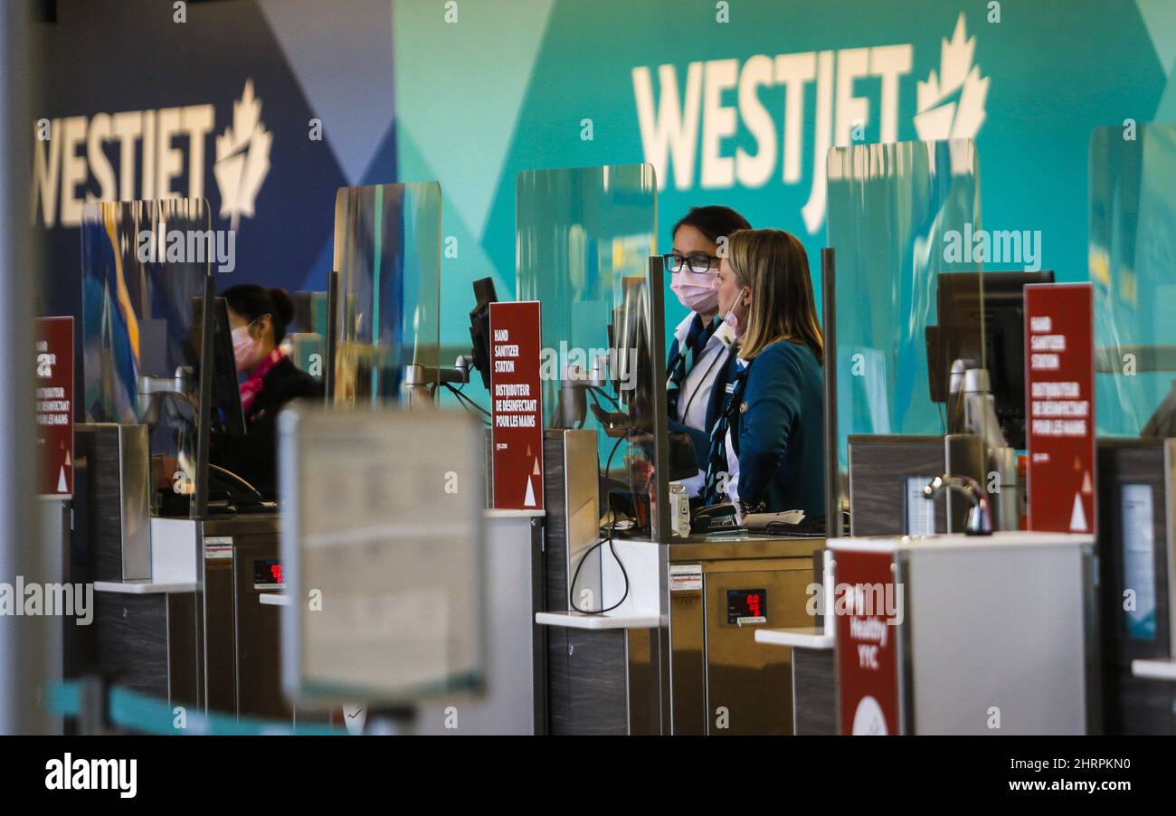 Westjet employees wearing masks wait for passengers at the Calgary