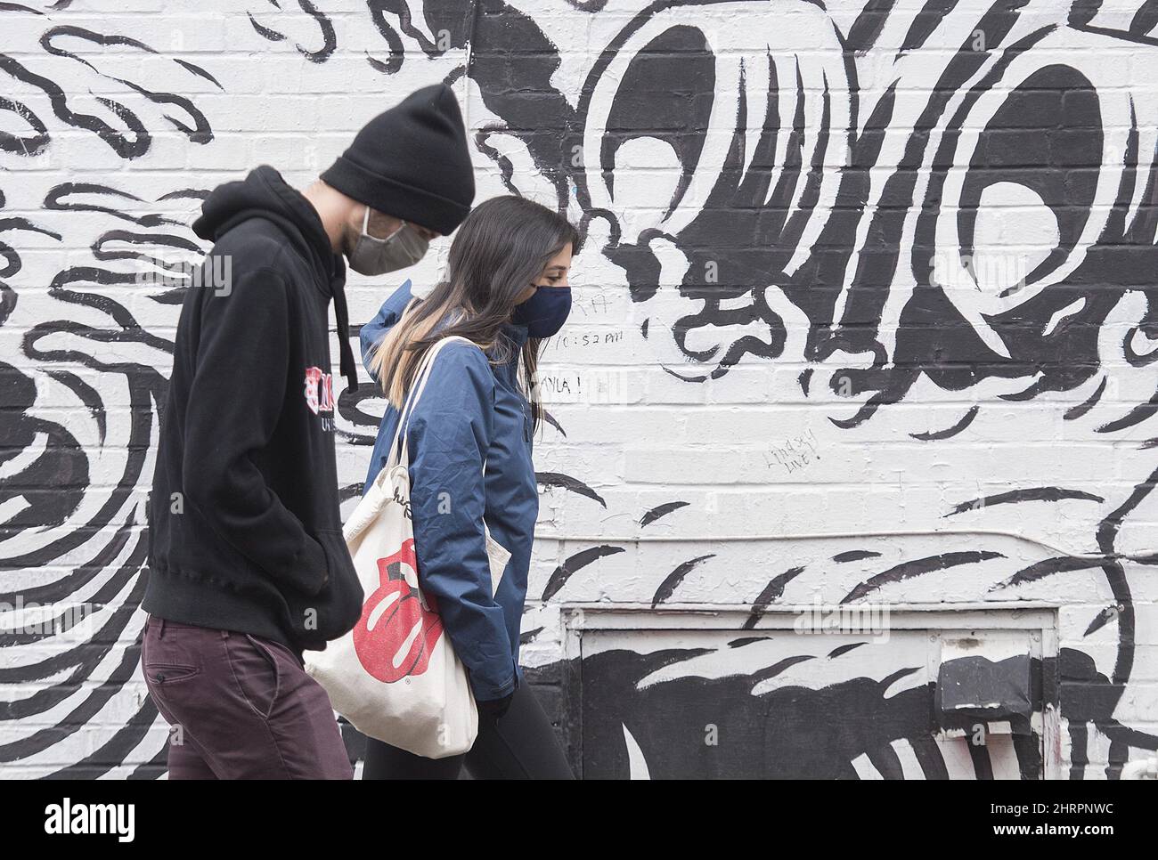 People wear face masks as they walk by a mural in Montreal, Sunday
