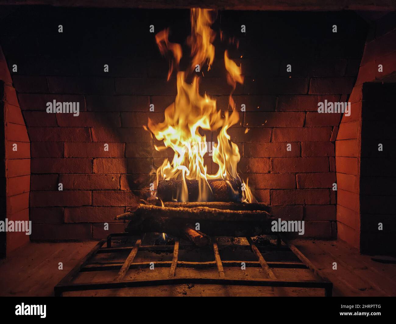 Roaring fire in a large rustic stone fireplace Stock Photo