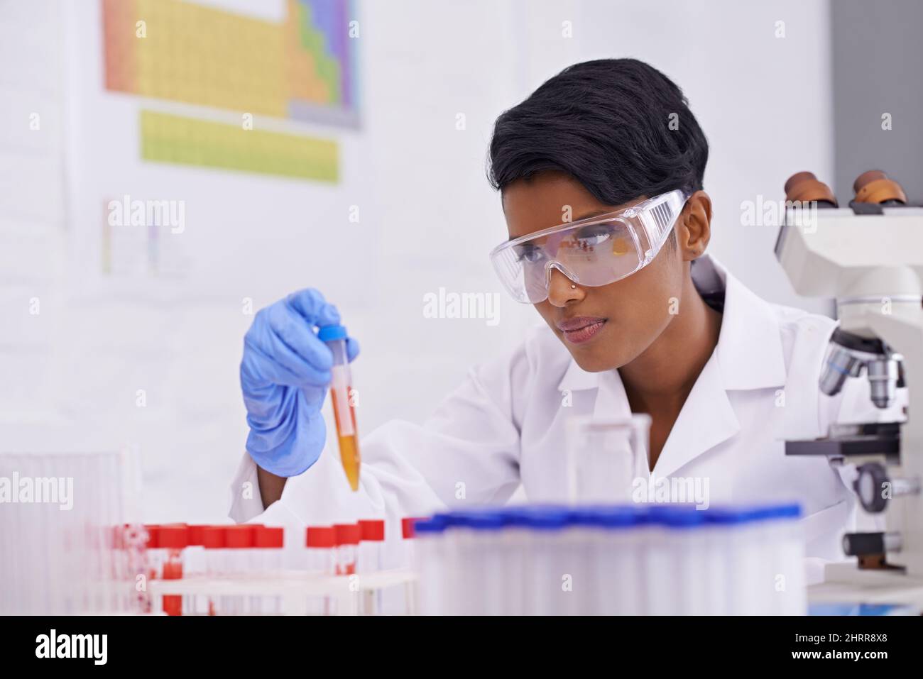 Daily labwork. A beautiful young scientist dropping a substance into