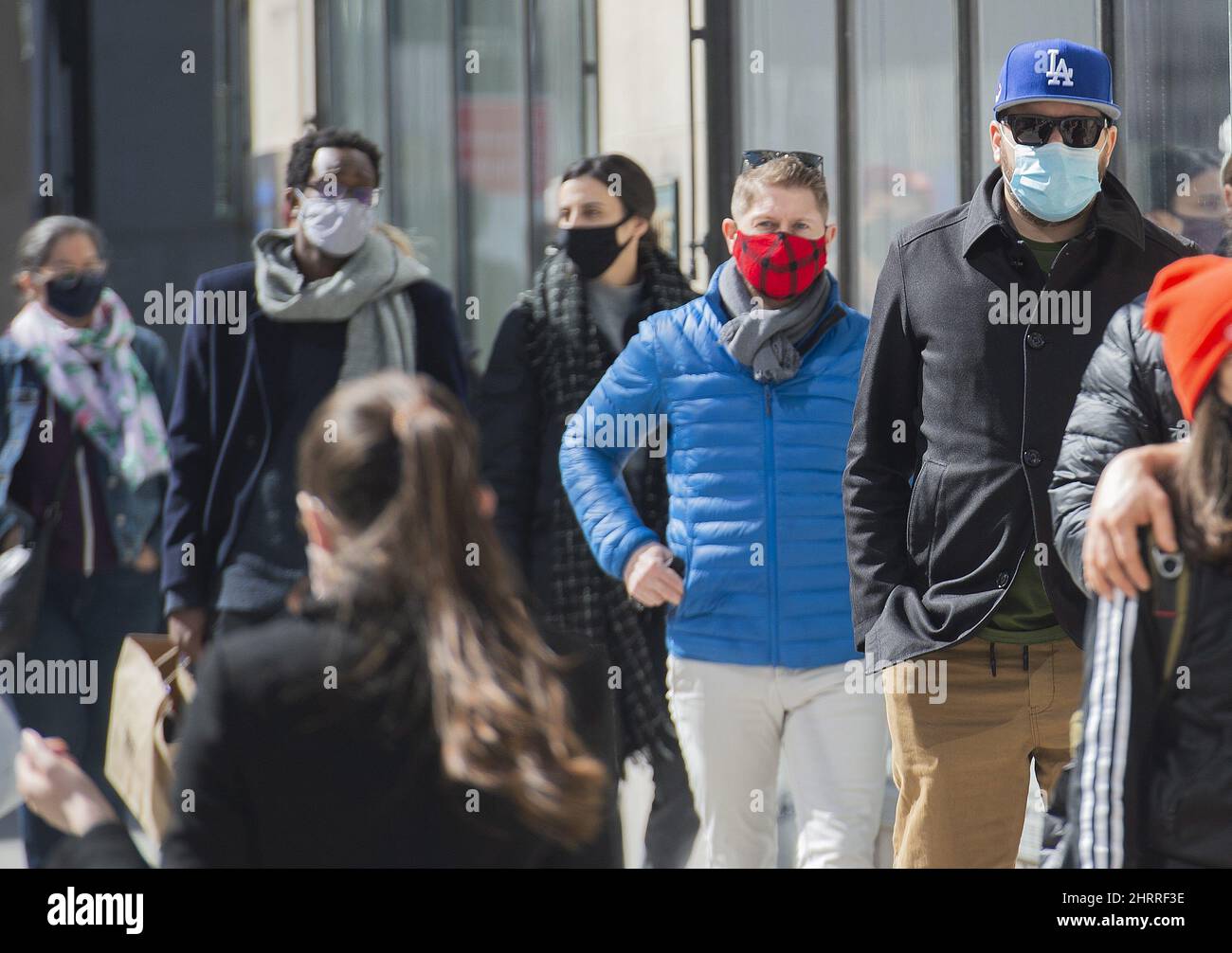People wear face masks as they wait to enter a store in Montreal, Sunday, March 21, 2021, as the