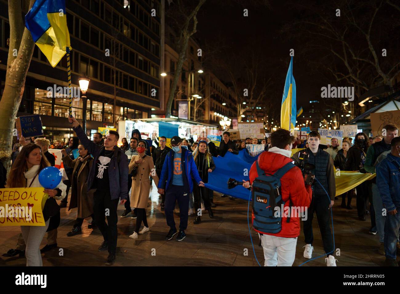 Barcelona, Spain - February 25, 2022: Walking Protest against the war and russian aggressive Vladimir Putin politic. Ukrainians in Spain in defense of Ukraine on plaza Catalunya place. Global military conflict, invasion. Reportage editorial photo from La Rambla Street Stock Photo