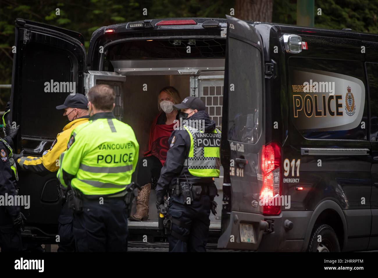 A woman sits in the back of a Vancouver police paddy wagon after being taken into custody after protesters attempted to march to the Lions Gate Bridge and shut it down to traffic as part of an Extinction Rebellion demonstration to call attention to climate change, in Vancouver, B.C., Monday, May 3, 2021. The group was stopped while en route with some taken into custody by police. THE CANADIAN PRESS/Darryl Dyck Stock Photo
