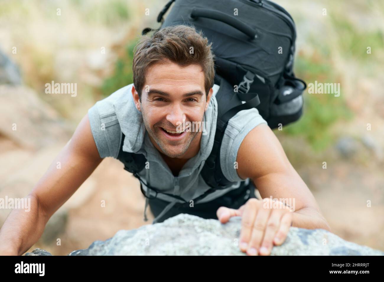 Climb every mountain. Young mountain climber smiling up at the camera. Stock Photo