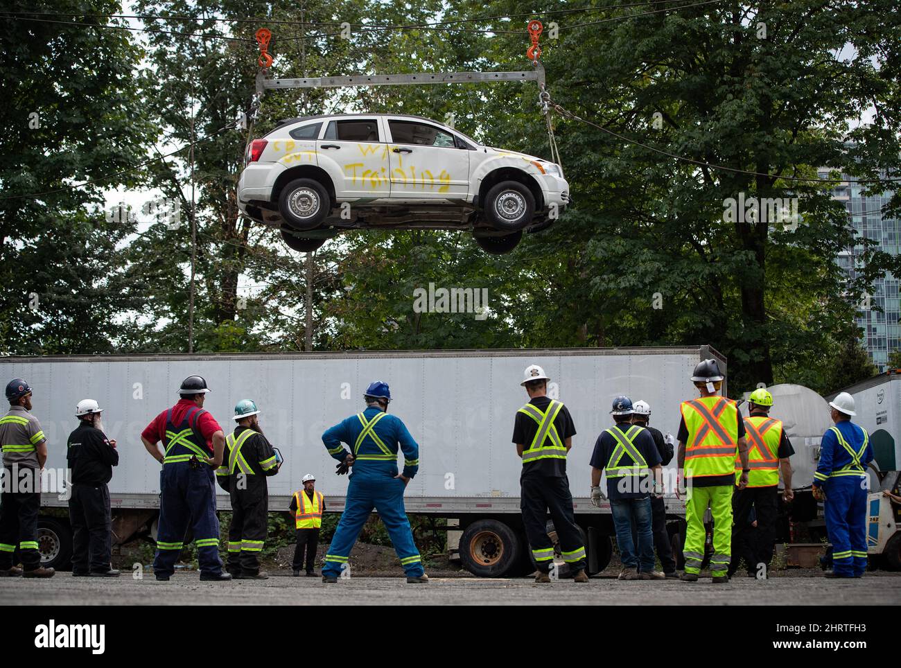 Heavy duty tow truck operators watch as a vehicle is lifted by winch