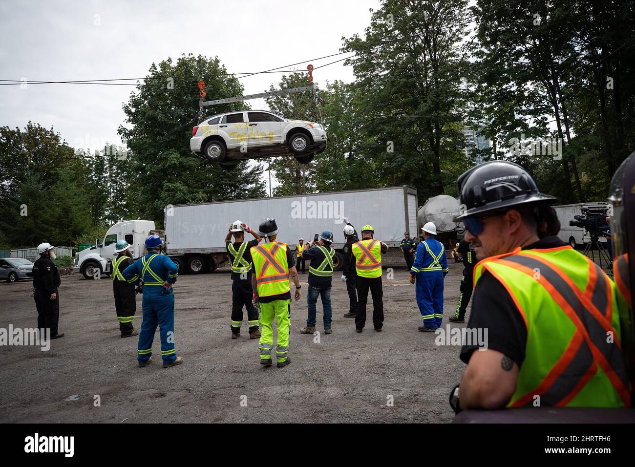 Heavy duty tow truck operators watch as a vehicle is lifted by winch