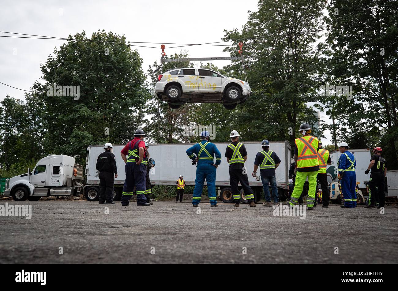 Heavy duty tow truck operators watch as a vehicle is lifted by winch