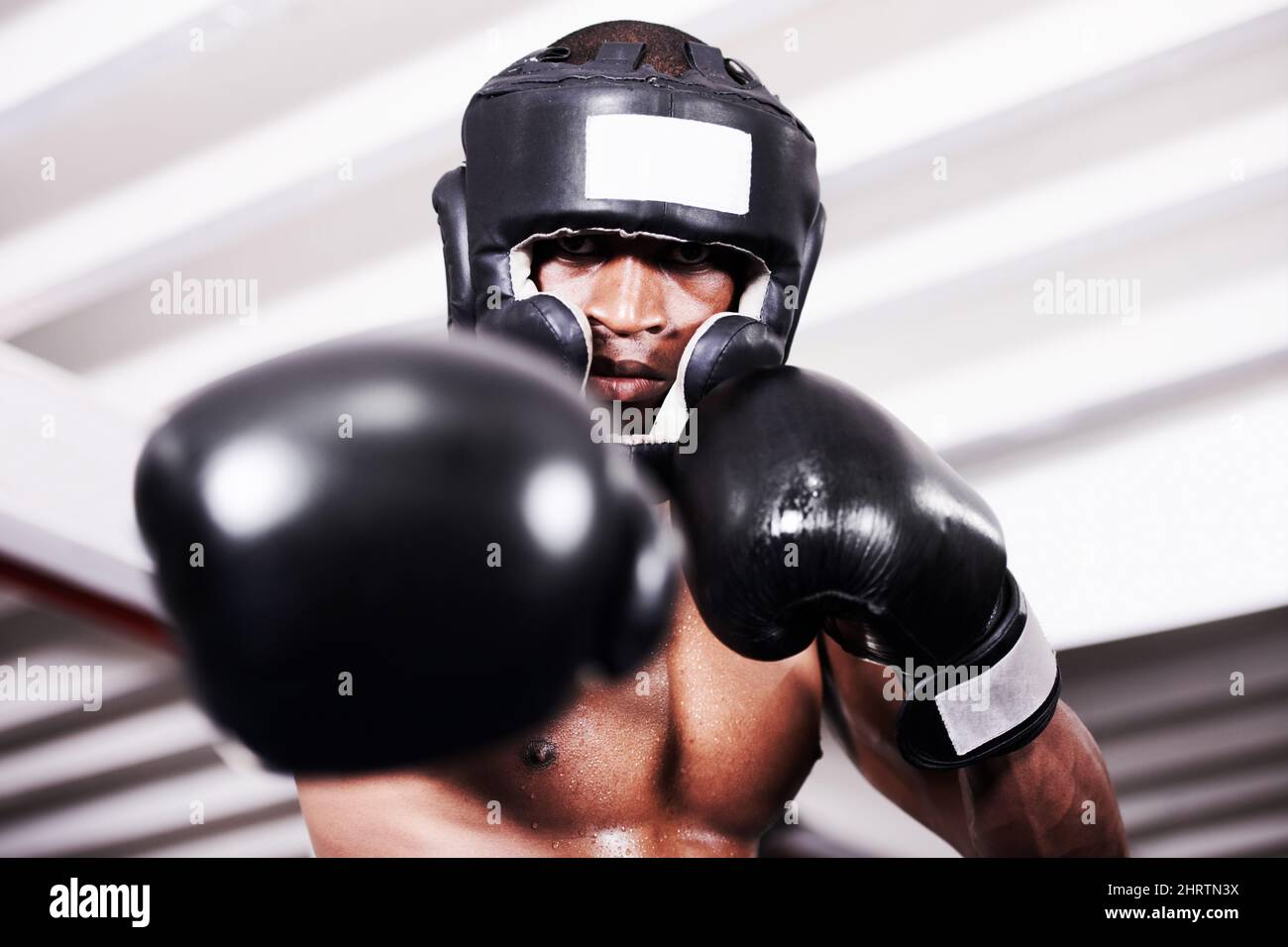 Ill take you one. An african american boxer wearing protective gear standing in the ring. Stock Photo