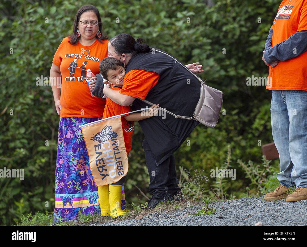 A young boy receives a hug as community members and area residents honour the National Day for