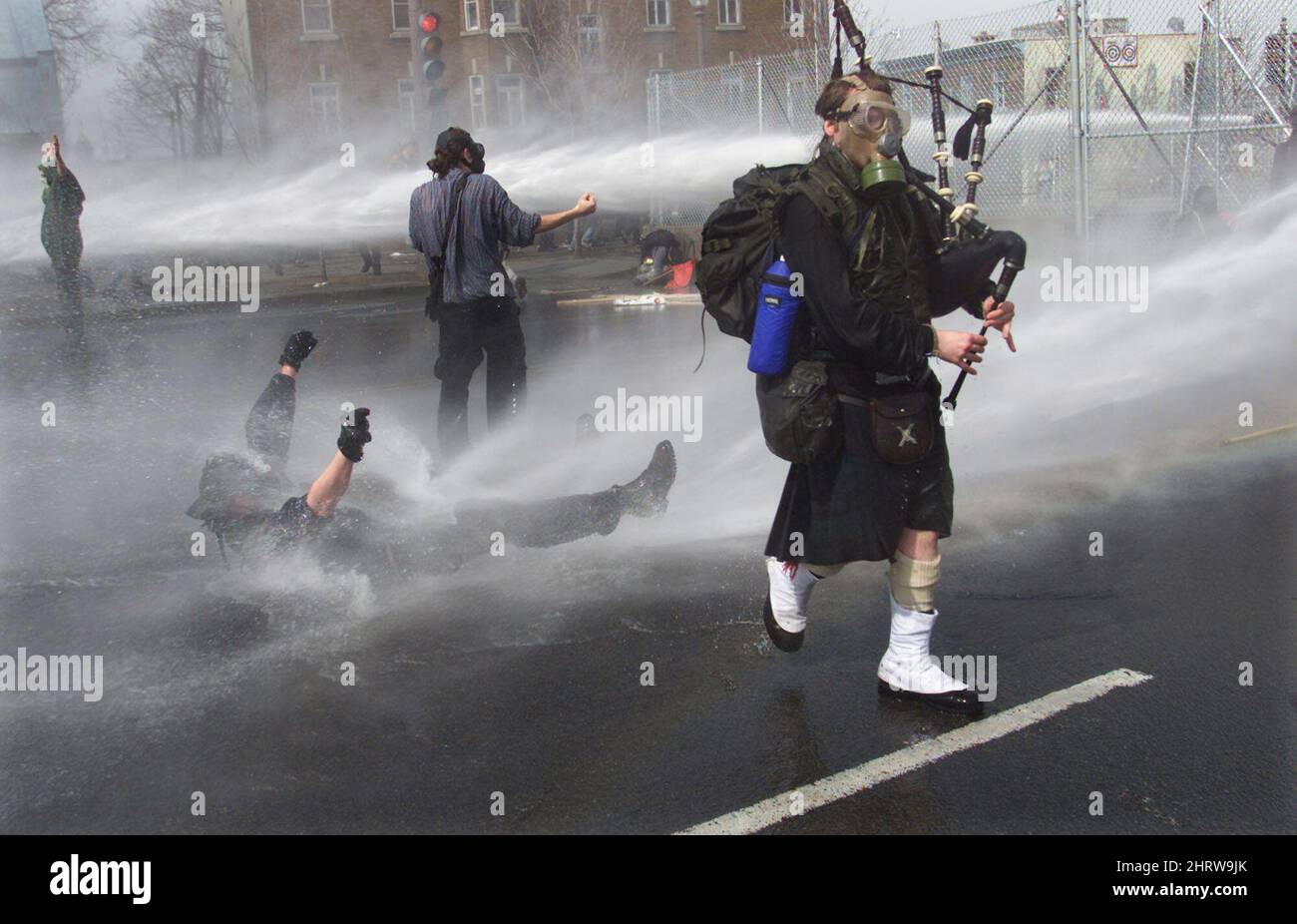 ** FILE ** In this Saturday, April 21, 2001 photograph by Canadian Press photographer Tom Hanson, a gas masked bagpiper plays his way past police water cannons as other protesters are sprayed outside the site of the Summit of the Americas in Quebec City. Award-winning Canadian Press photojournalist Hanson, a fierce champion of journalistic rights whose sometimes brusque manner belied a devoted husband with a gentle soul, died suddenly Tuesday, March 10, 2009 after collapsing while playing hockey. (AP Photo/The Canadian Press, Tom Hanson) Stock Photo