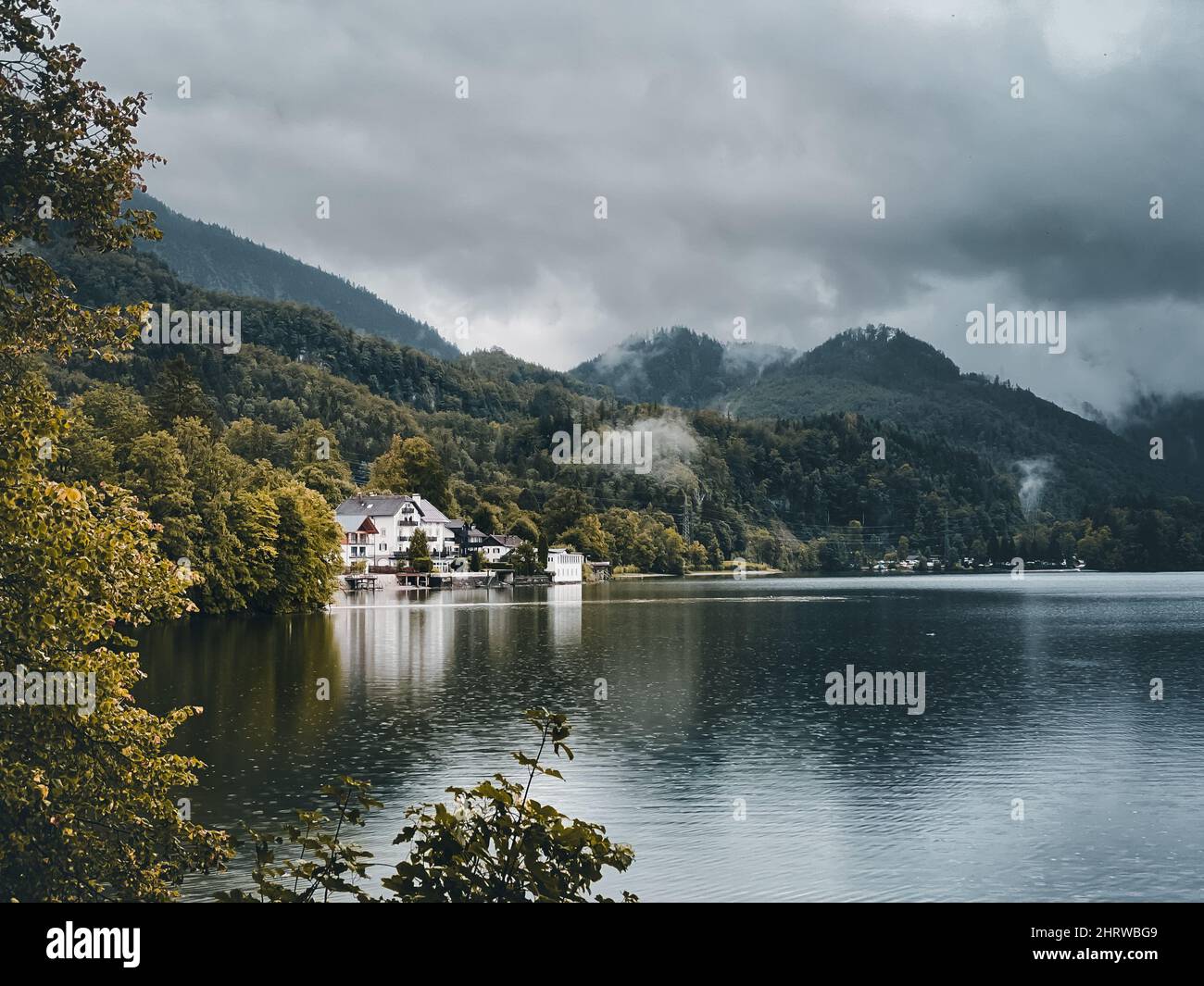 House surrounded by a beautiful lake and trees under a gray cloudy sky in Geretsried Stock Photo