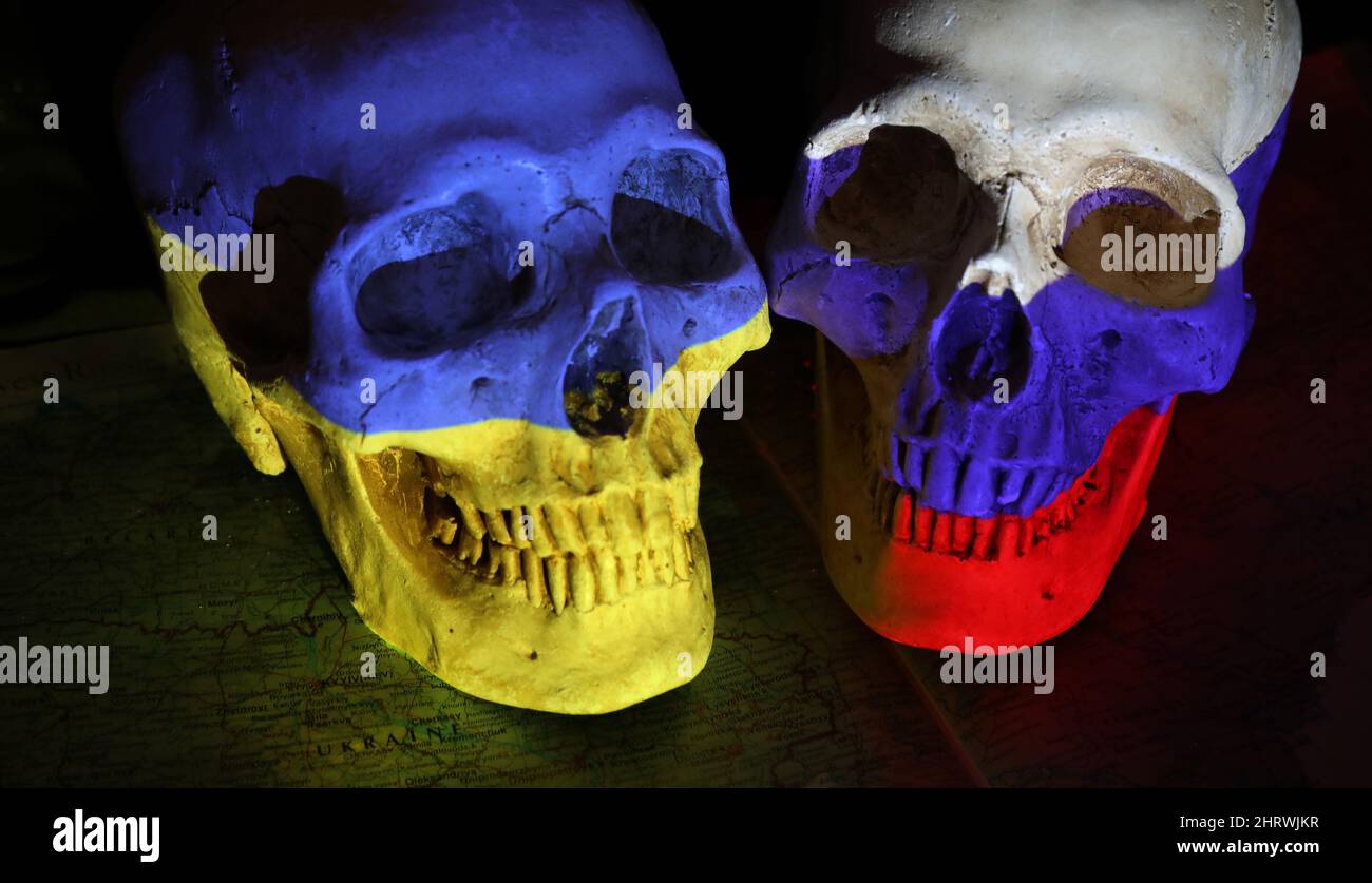 Two opposing skulls colored with the national flags of Russia and Ukraine sitting on top op a darkened map of the region and a black background. The w Stock Photo