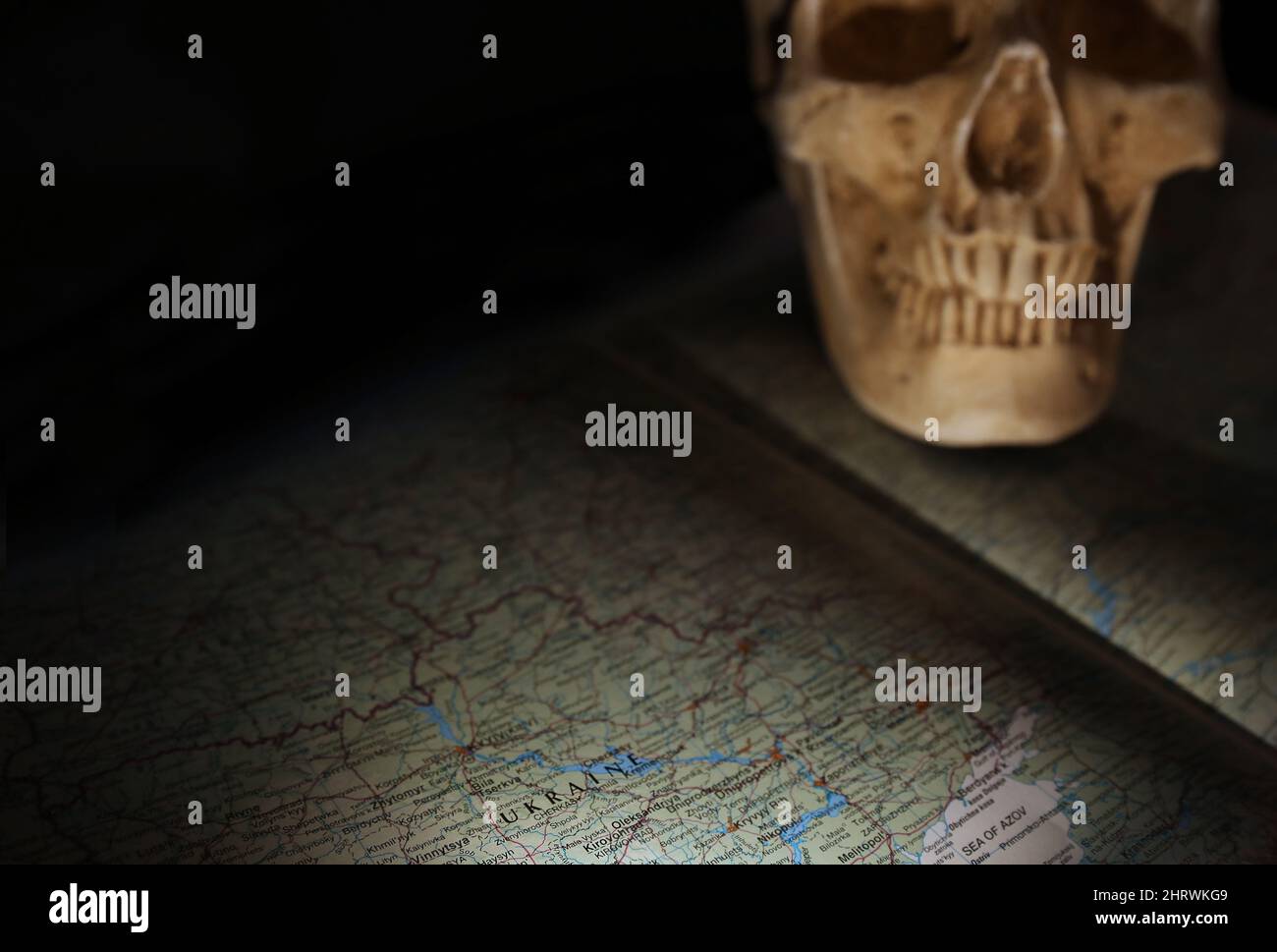 The map and geography of the Ukraine region in a darkened threatening space. Ominous deliberately blurred skull representing conflict and death with Stock Photo