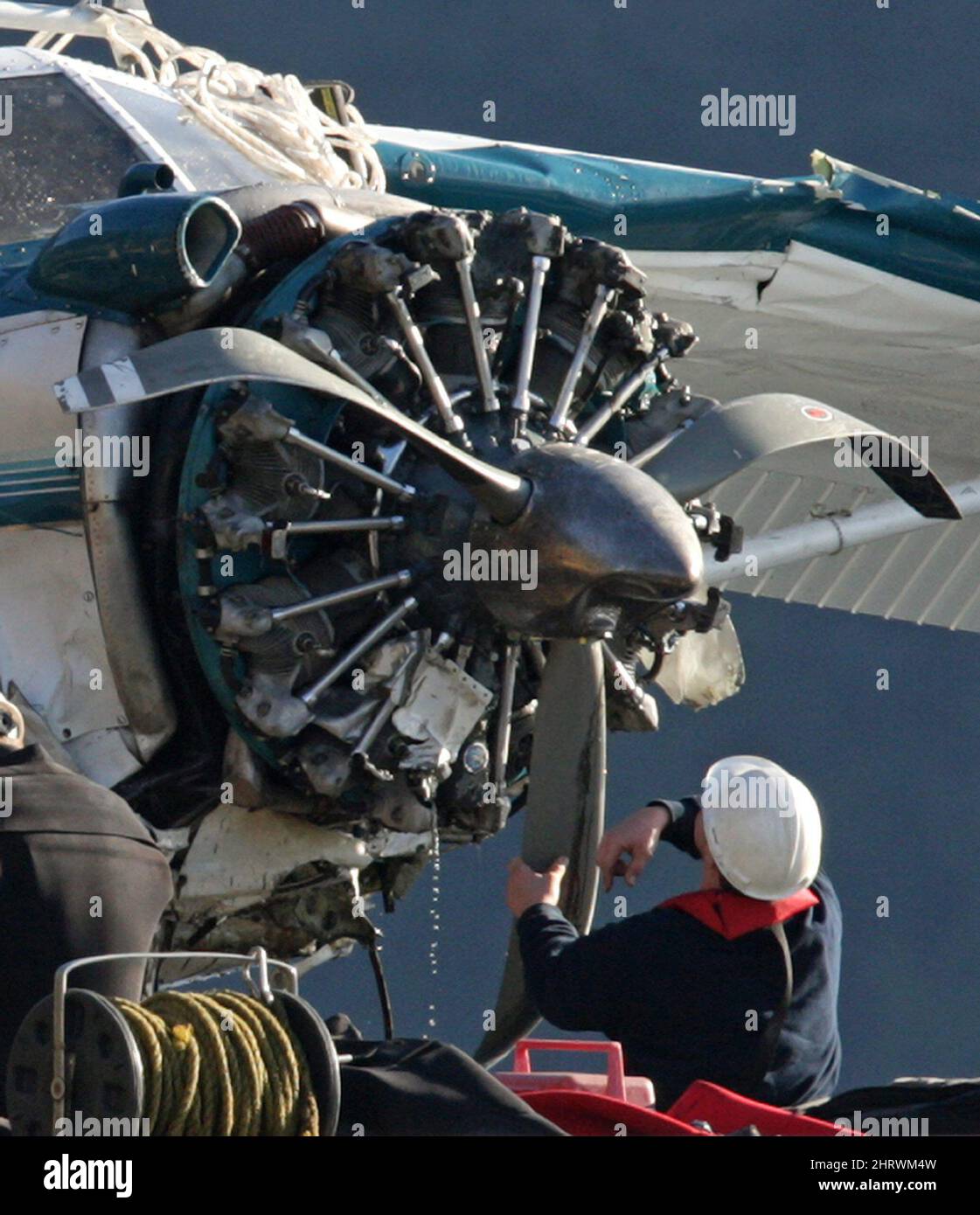 The wreckage of a float plane is lifted from the water onto a barge in ...