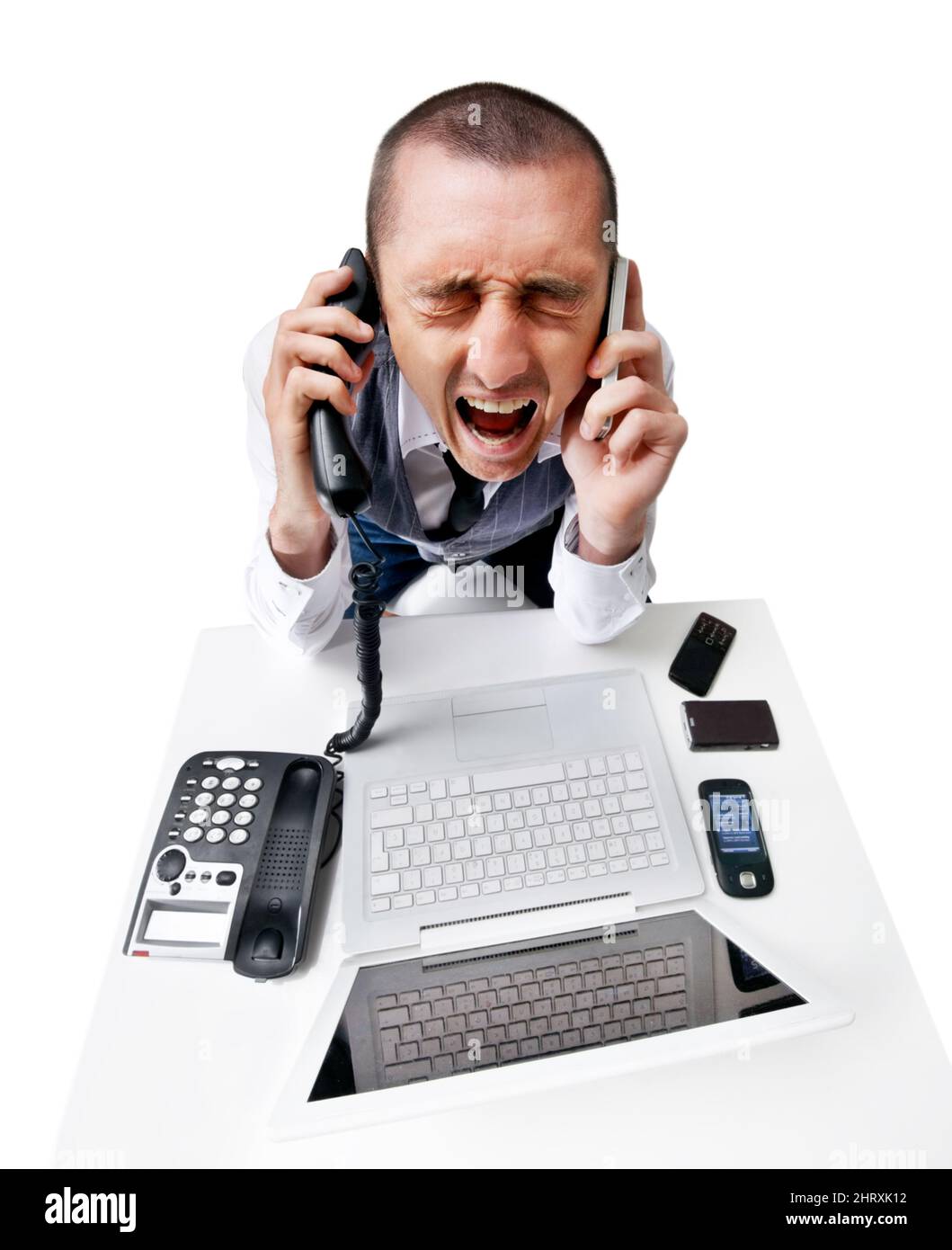 Dealing with too much. A frustrated young man trying to answer multiple phones and feeling stressed. Stock Photo