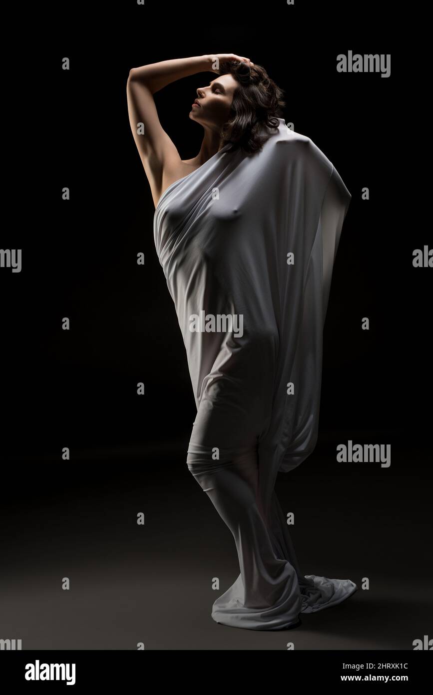 Woman wrapped in cloth outstretching arms in studio Stock Photo