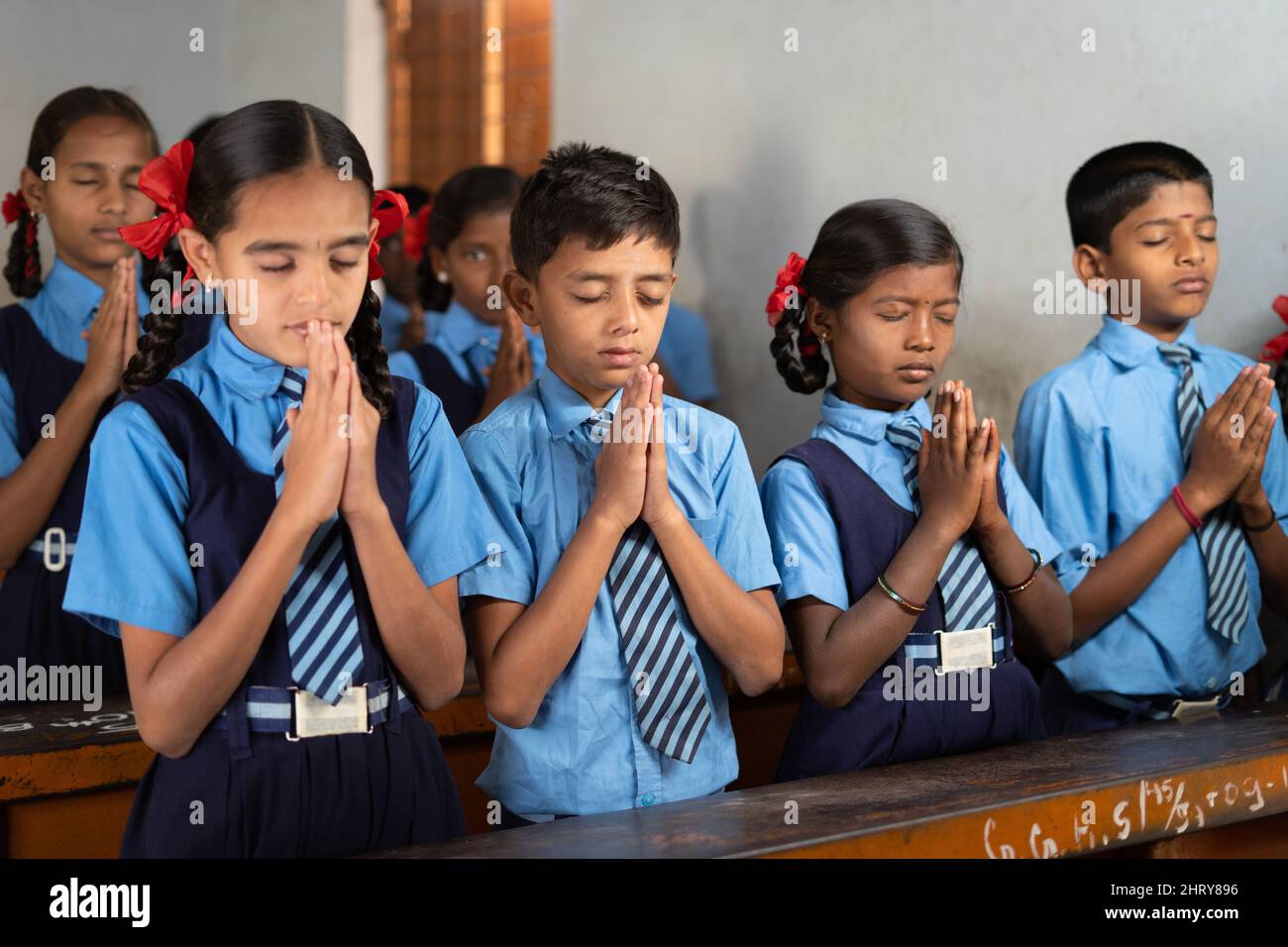 Students at classroom doing morning prayer with closed eyes - concept of wisdom, friendship, development and discipline. Stock Photo