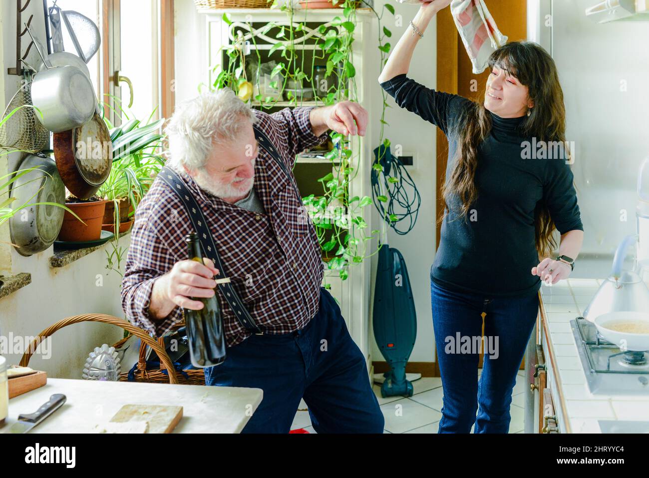 caucasian senior man drinking wine and getting drunk at home stressing younger hispanic wife - alcoholism and domestic violence concept Stock Photo