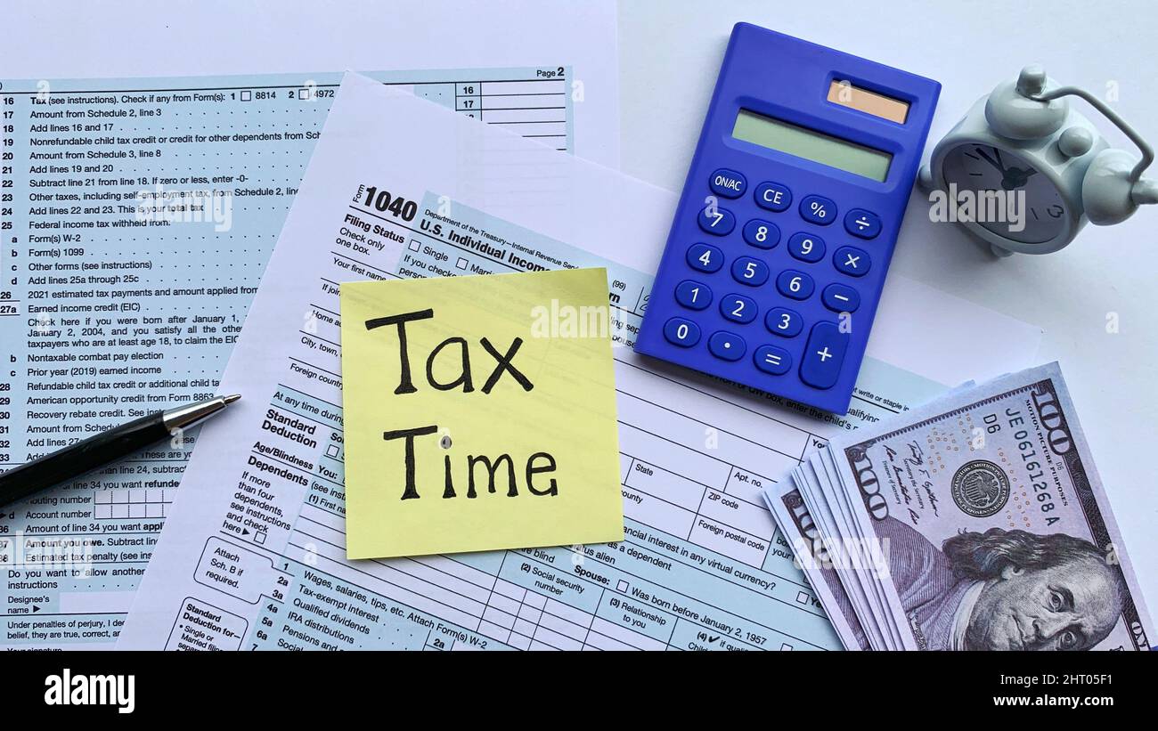 Note Tax Time Top view of text on yellow notepad - Tax time. With tax form, bank ...