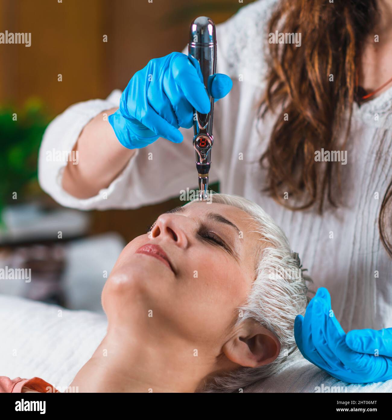Woman receiving forehead treatment with meridian therapy pen Stock Photo