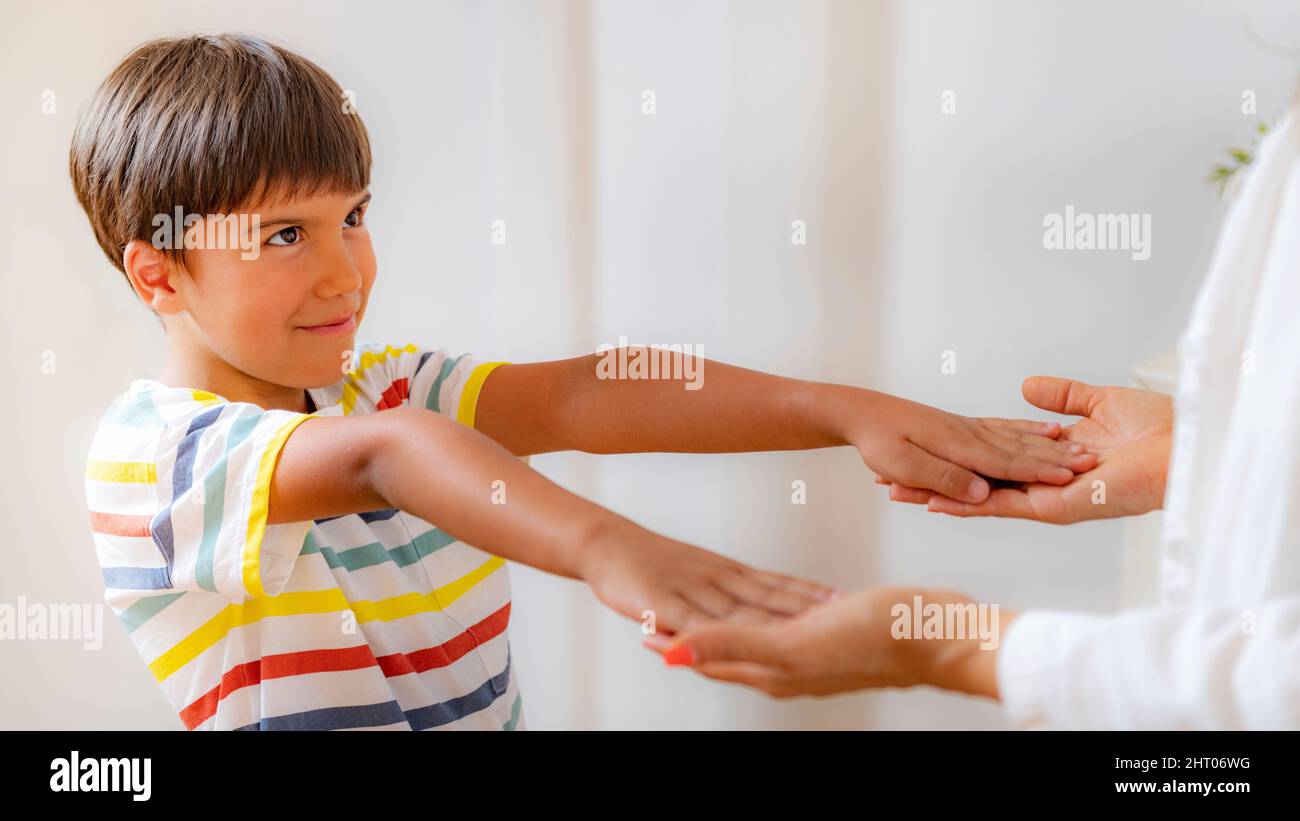 Boy holding arms raised during a physical medical exam Stock Photo