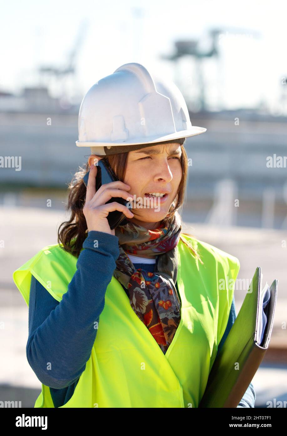 Sorting out the construction needs. A female construction worker talking on the phone. Stock Photo