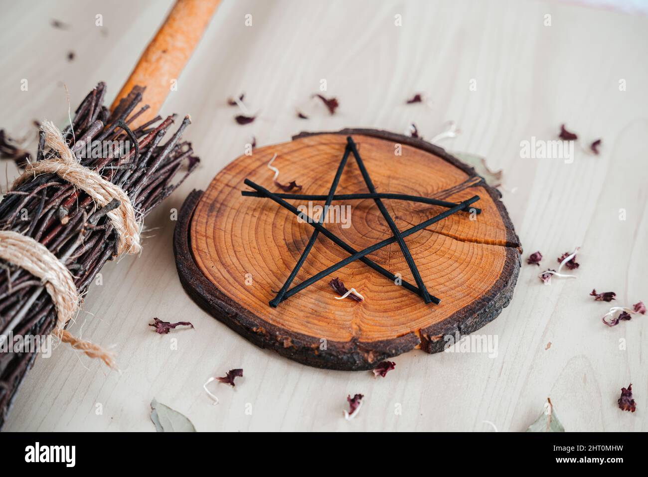 Hand made DIY besom broom and black pentagram on a white wooden table. Witchy closeup of ritual witchcraft items Stock Photo
