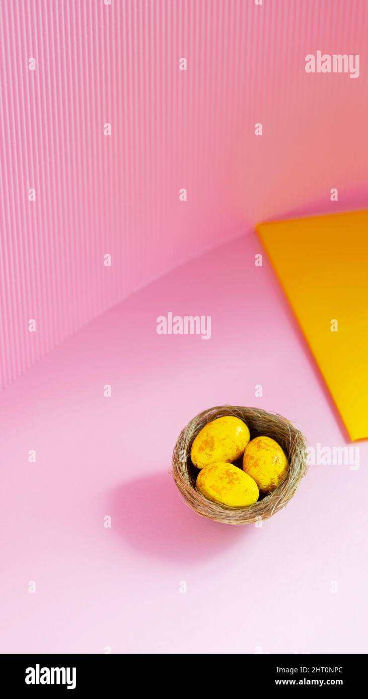 Easter eggs in a natural nest. Painted yellow-golden eggs on a pink background. Easter minimalistic concept. Copy space Stock Photo