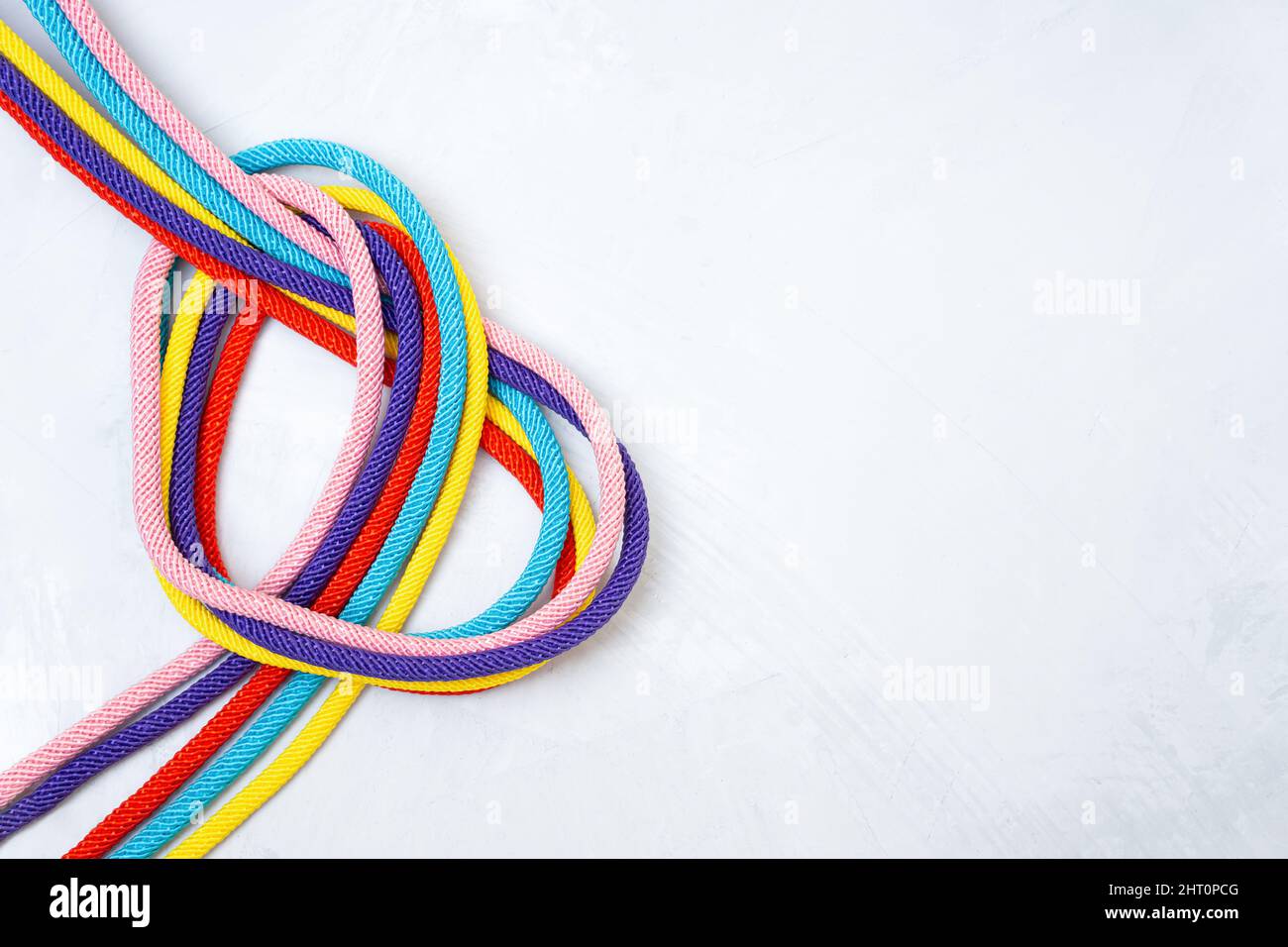 Heart shaped made of five multicolored cords twisted on a concrete background. Creative relationship concept. Stock Photo