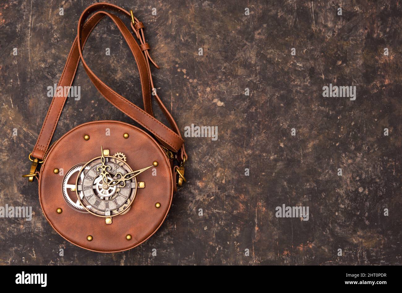 Circle steampunk leather bag with a clockwork on the outside on a grungy background. Stock Photo