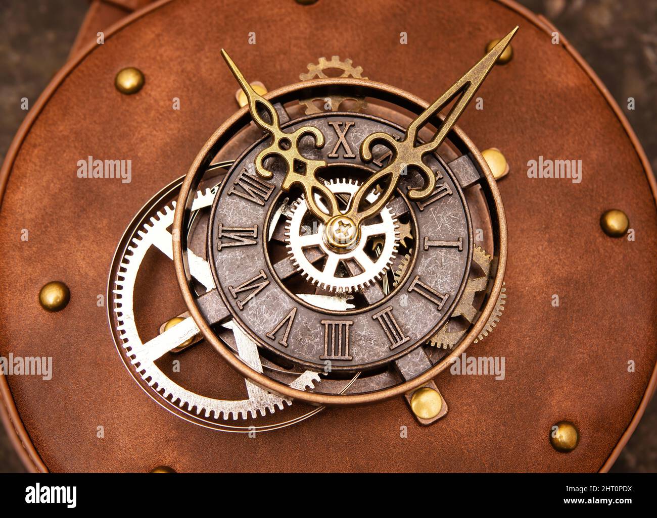 Close-up of a clock mechanism of a circle steampunk leather bag on a grungy background. Stock Photo