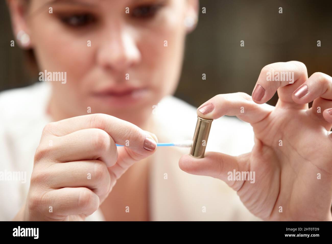 Residue might reveal the criminal. A forensic scientist applying an ear bud to a bullet. Stock Photo