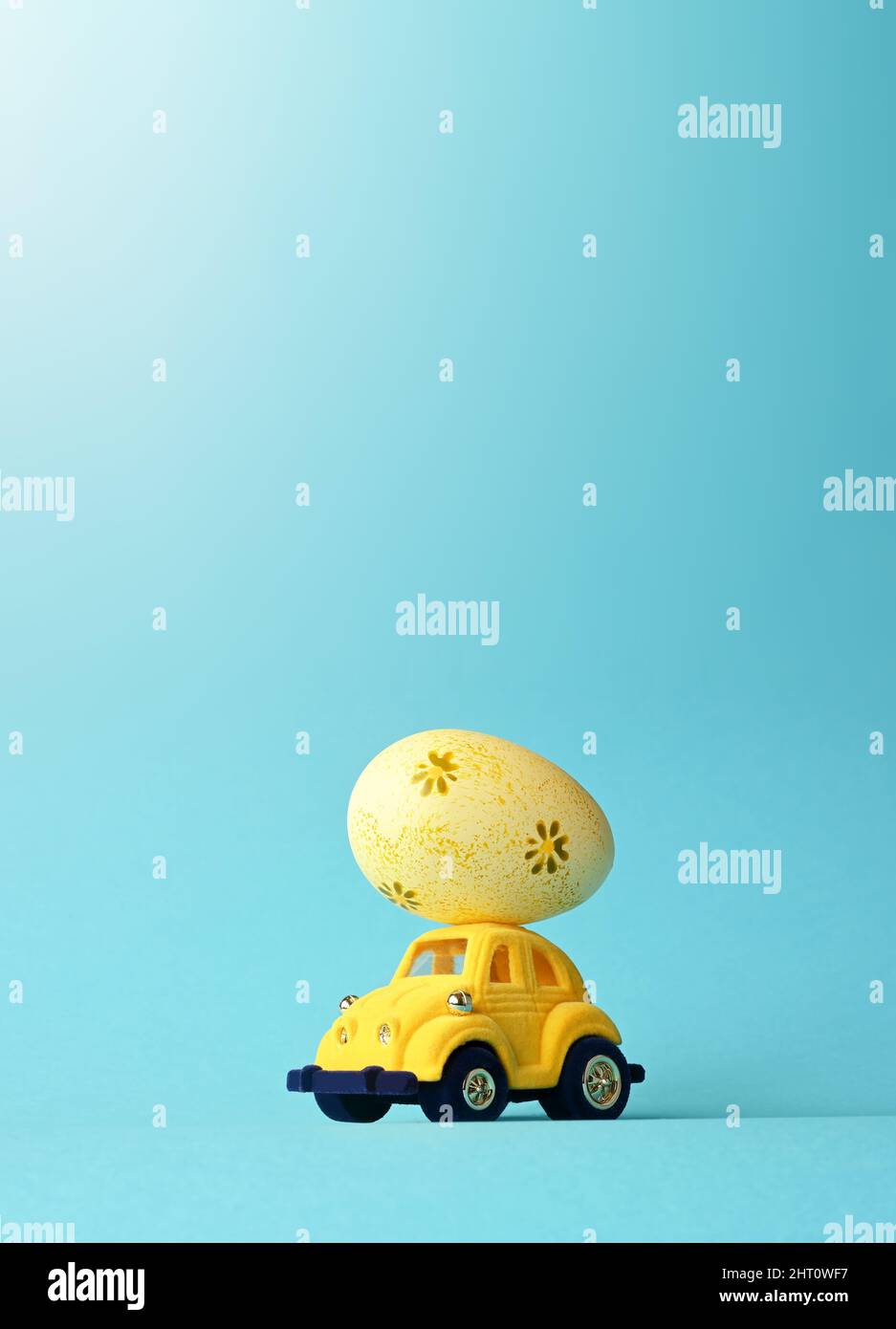 One Easter egg on a small car on a blue background. Copy space. Easter card. Stock Photo