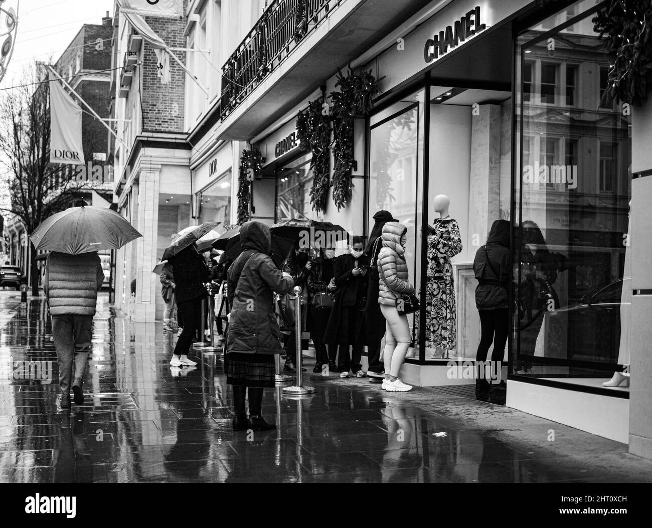 A grayscale shot of people lined up outside the Channel store in Mayfair, London Stock Photo