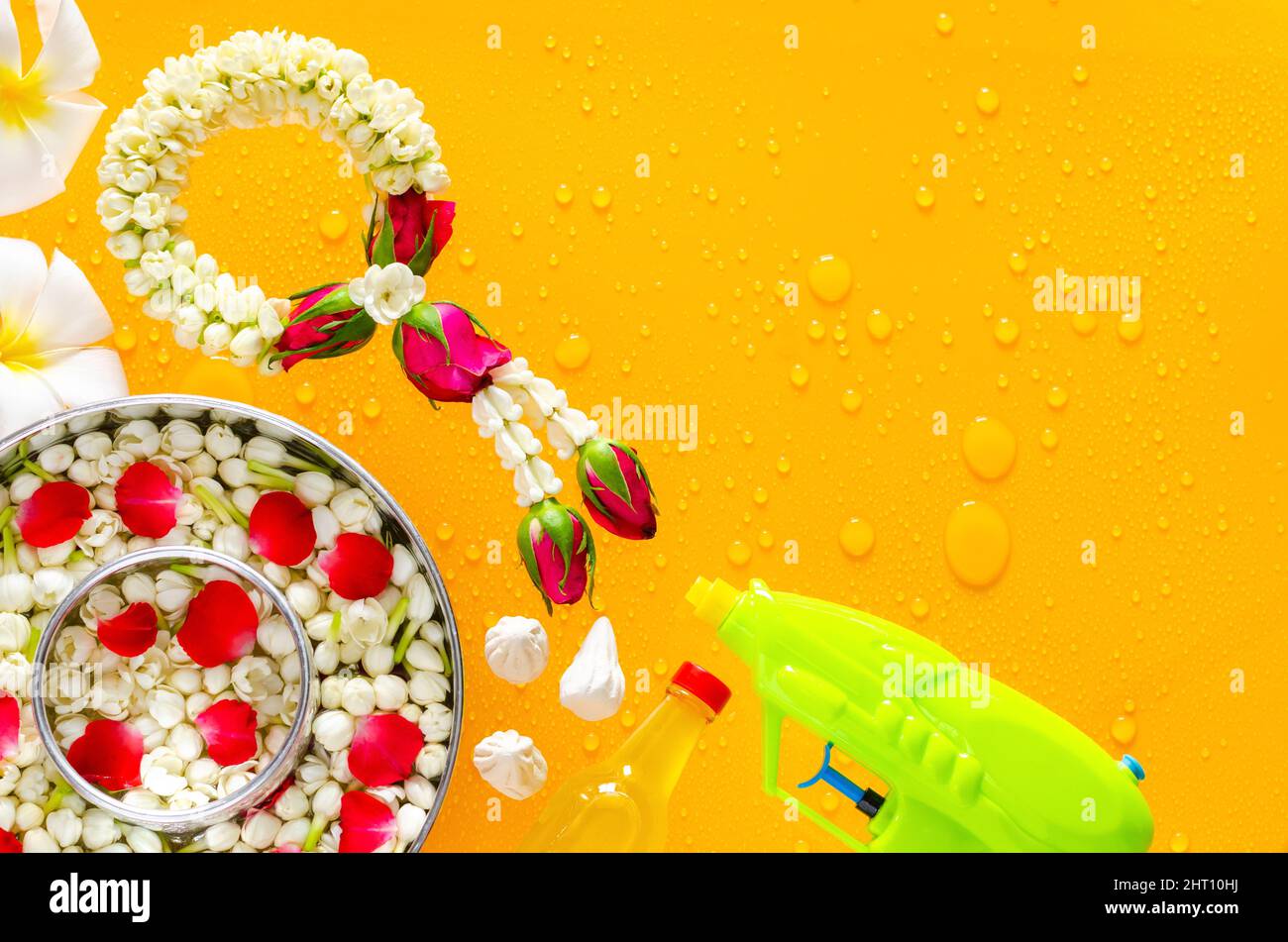 Songkran festival background with jasmine garland, water gun, flowers in water bowls, scented water and marly limestone put on clear mirror that have Stock Photo