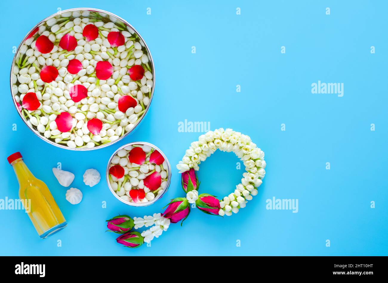 Songkran festival background with flowers in water bowls, jasmine garland, scented water and marly limestone for blessing on blue background. Stock Photo
