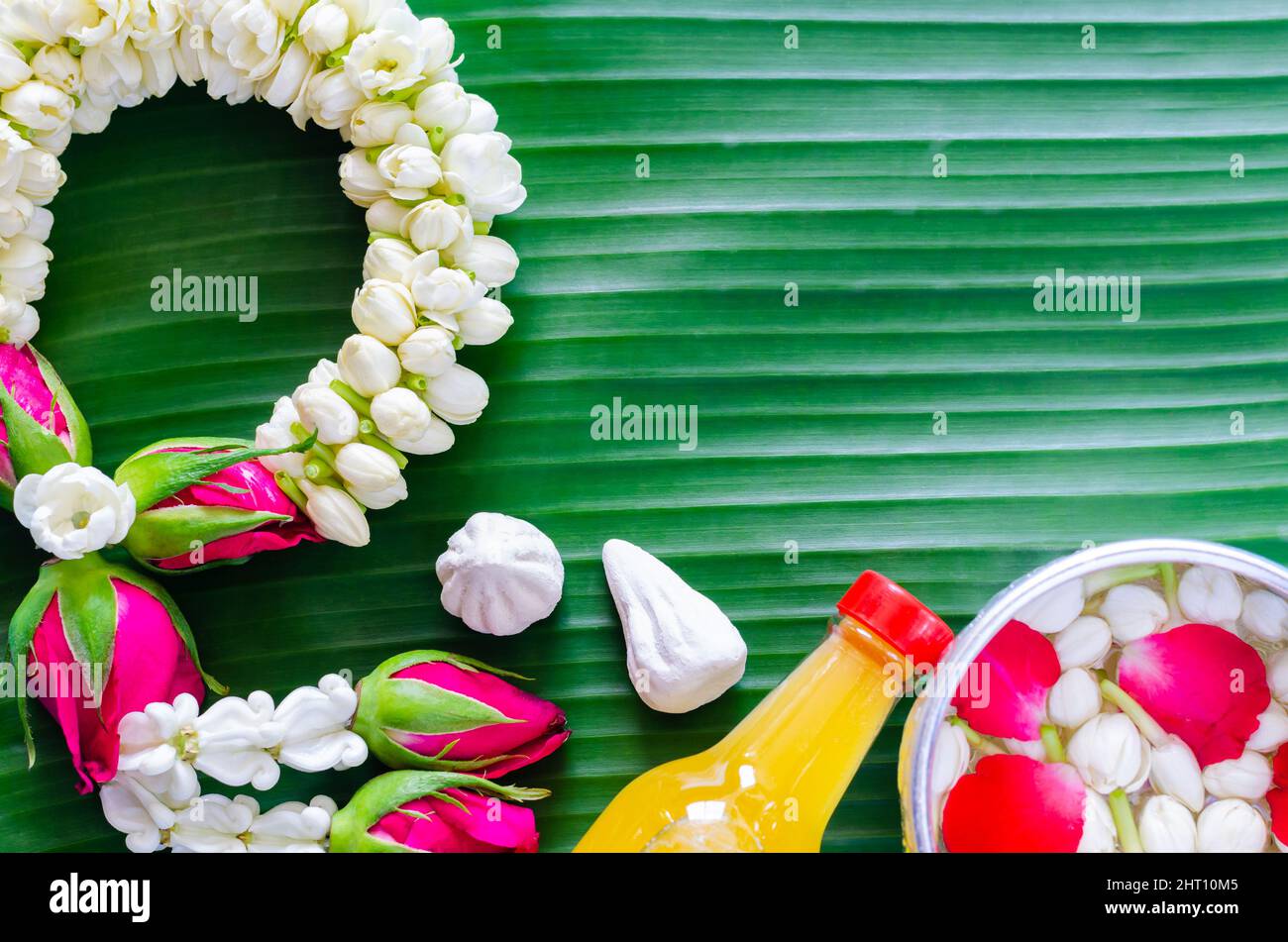 Songkran festival background with jasmine garland, scented water and marly limestone, flowers in water bowl for blessing on banana leaf background. Stock Photo